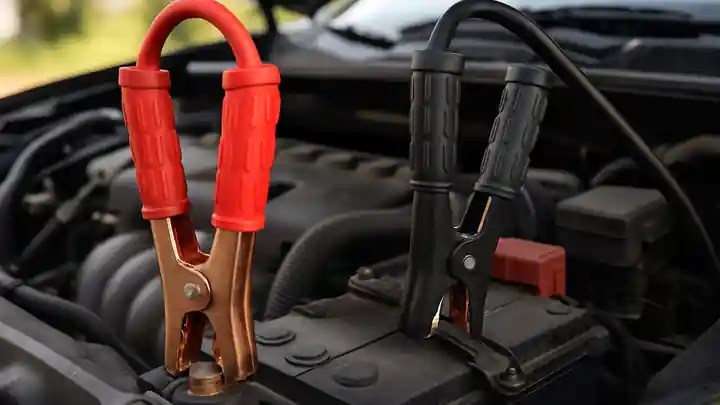 Jumper cables connected to a car battery under the hood in Anna, TX